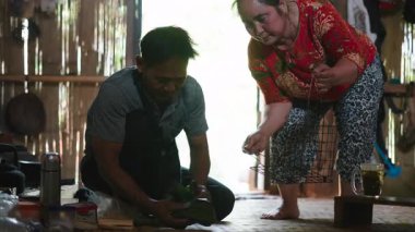 Southeast Asian couple prepares traditional food inside a rustic house using traditional techniques - 4K Horizontal