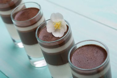 Arka arkaya dört bardak çikolatalı tatlı standı, turkuaz arka planda, tatil ve tatlı konsepti