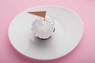 Beyaz kremalı, süs bayraklı, pembe bir yüzey üzerinde tatil.