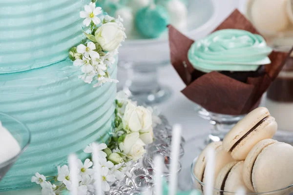 お祝いのテーブルの上のウェディングケーキ 花で飾られたターコイズケーキ 他のお菓子やデザートの横にある ケーキに焦点を当て ロイヤリティフリーのストック写真