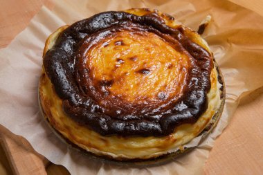 Yeni pişmiş İspanyol Bask peynirli keki parşömen kağıdının üstünde, masada, yakın plan.