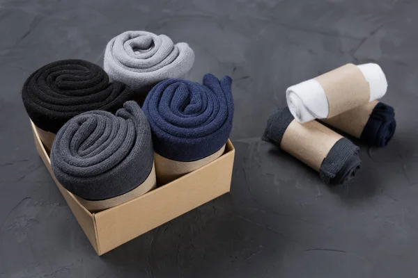 Four rolled men\'s socks in a box, and three rolls of socks lie side by side, concept