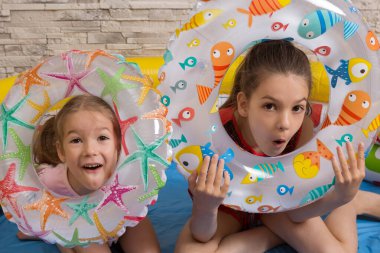 two girls having fun at home, with rubber rings, want to swim in the sea, the concept of self-isolation, close-up