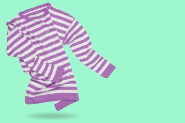 Sweater with a lilac-white stripe, as if dancing, concept on a light green background, copy space