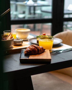 Kahve, meyve suyu, kruvasan, avokado tostları ve yoğurtlu iki kişilik kahvaltı masası.