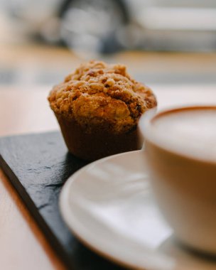 Latte ve çikolatalı kek bir kahve dükkanında ve üzerinde sarı bir çiçek ve güzel bir iç tasarım olan bir masanın üzerinde.