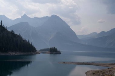 Kanada Rocky Dağları 'nda yüksek dağ göllerinin arka planında sis olan dramatik manzaralar.