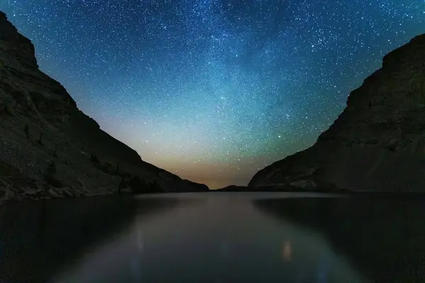 Güzel yıldızlı gökyüzüne ve Samanyolu 'na sahip gece manzaraları Kanada Kayalıkları' ndaki bir dağ gölünün arka planına karşı.