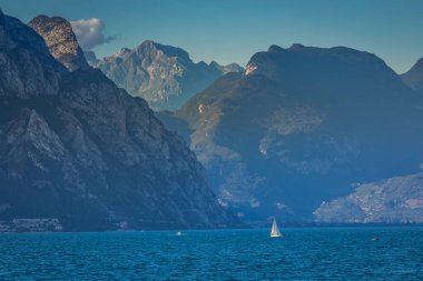 Sailing alone in Lake Garda with dramatic landscape near Riva del Garda, Northern Italy