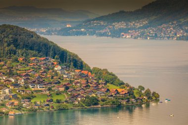 İsviçre Alpleri ve Thun Gölü 'nün dramatik günbatımında feribot manzarası, Interlaken, İsviçre