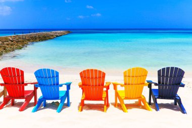 Colorful wooden chairs on white sand beach in Aruba, Duth Caribbean at sunny day