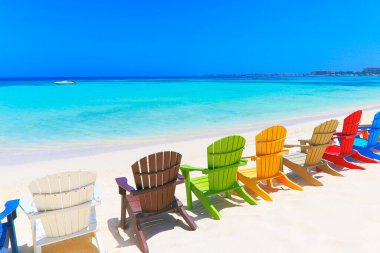 Colorful wooden chairs on white sand beach in Aruba, Duth Caribbean at sunny day