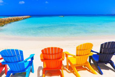 Colorful wooden chairs on white sand beach in Aruba, Duth Caribbean at sunny day