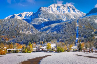 Road into snowy mountain and pine woods in bavarian Alps at autumn, Germany