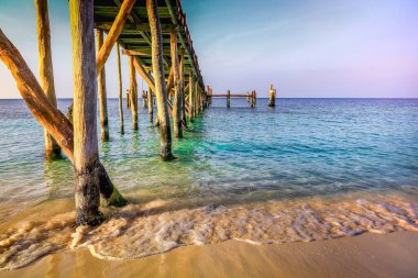 Tropical paradise, sand beach in caribbean with palapa and pier at sunset, Cancun, Mexico