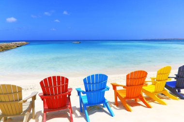 Colorful wooden chairs on white sand beach in Aruba, Duth Caribbean at sunny day