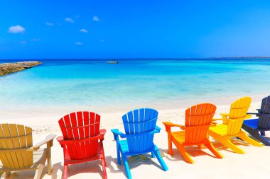 Colorful wooden chairs on white sand beach in Aruba, Duth Caribbean at sunny day clipart