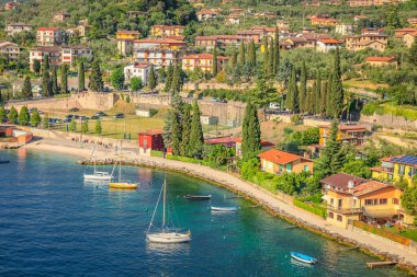 Above idyllic Lake Garda with alps and sailboats in Malcesine at sunrise, Italian alps