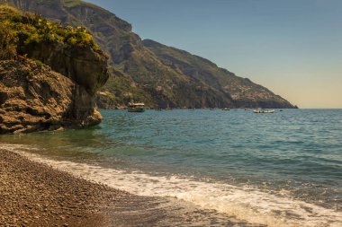 Idyllic Positano beach with cliffs and marina with boats and yacht, amalfi coast, Italy
