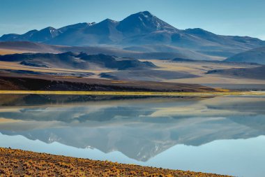 Salt lake reflection and idyllic volcanic landscape at Sunset, Atacama desert, Chile border with Bolivia