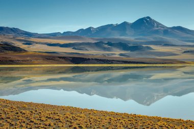 Salt lake reflection and idyllic volcanic landscape at Sunset, Atacama desert, Chile border with Bolivia