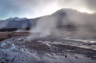 Geysers El Tatio with river and Peaceful dramatic volcanic landscape at sunrise, Atacama Desert, Chile