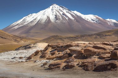 Dramatic snowcapped volcanic landscape in Piedras Rojas at sunny day, Atacama Desert, Chile