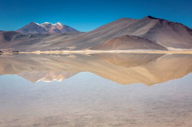 Salt lake reflection and idyllic volcanic landscape at sunrise, Atacama desert, Chile border with Bolivia