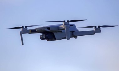 İHA gökyüzünde uçuyor. Doğayı gözlemlemek ve filme almak için video kameralı radyo kontrollü bir kuadkopter..