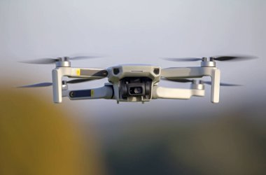 İHA gökyüzünde uçuyor. Doğayı gözlemlemek ve filme almak için video kameralı radyo kontrollü bir kuadkopter..