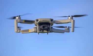 İHA gökyüzünde uçuyor. Doğayı gözlemlemek ve filme almak için video kameralı radyo kontrollü bir kuadkopter..