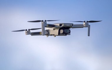 Drone flying in the sky. Radio-controlled quadcopter with a video camera for observing and filming nature. clipart