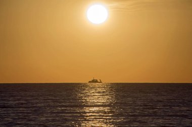 Ufukta bir gemi olan yumuşak turuncu gün batımı. Metin ve başlıklar için uygun stil arkaplanı.