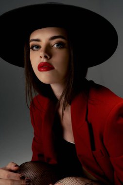 Young girl in a hat and a red jacket poses in the studio