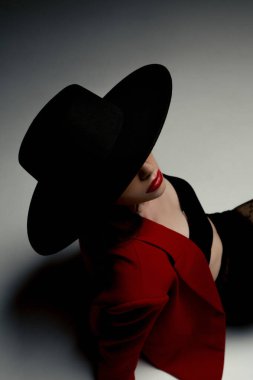 Young girl in a hat and a red jacket poses in the studio