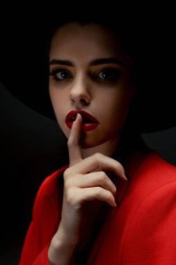 Young girl in a hat and a red jacket poses in the studio