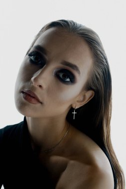 Stüdyoda siyah elbiseyle poz veren zarif genç bir kadının portresi.