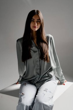 Bir fotoğraf stüdyosunda poz veren kazaklı ve eşofmanlı güzel bir kız.