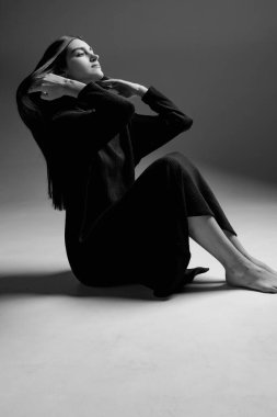 Siyah elbiseli genç bir kız fotoğraf stüdyosunda poz veriyor.