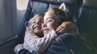 Birbirlerine kenetlenmiş kardeşler uçak koltuğunda birbirlerine sarılıyorlar. Tatil yerlerine varmayı endişeyle beklerken gerçekten mutlular.