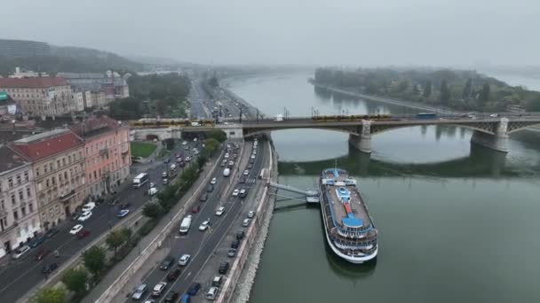 布达佩斯玛格丽特桥或玛吉特的空中景观隐藏在多瑙河的堤岸上 城市的公共交通 穿过大桥的黄色电车 — 图库视频影像