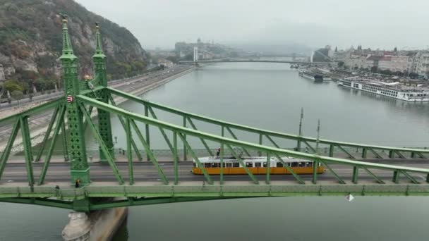 布达佩斯的空中景观隐藏了自由桥或自由桥 连接布达和佩斯穿过多瑙河 一辆有轨电车沿着标志性的桥在历史名城内穿梭 — 图库视频影像