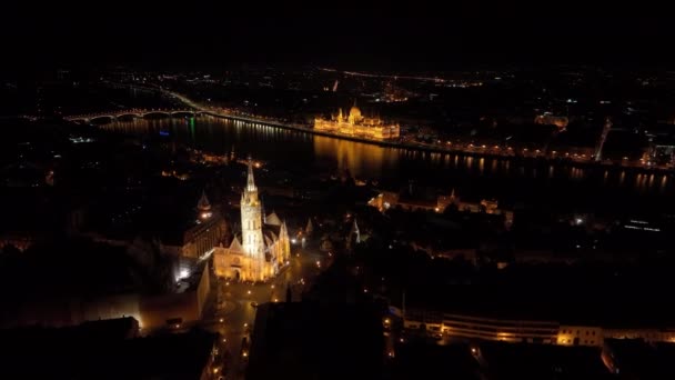 匈牙利布达佩斯 以匈牙利议会为背景 飞越著名的渔民城堡和马蒂亚斯教堂飞往多瑙河 夜间航拍 — 图库视频影像