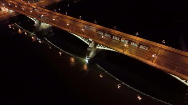 Budapeşte Margaret Köprüsü ya da Margit 'in hava manzarası Tuna Nehri' nin üzerinde, geceleri setin üzerinde saklanıyordu. Şehirde toplu taşıma. Sarı tramvay köprüden geçiyor.