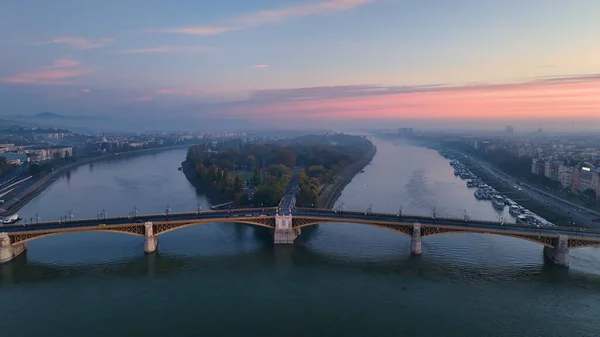 stock image Aerial view of Budapest Margaret Bridge or Margit hid over River Danube, embankment at sunrise. Public transport in the city