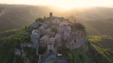 İtalya 'nın Lazio eyaletinin Viterbo kentindeki Tiber Nehri vadisine bakan volkanik bir tuff tepesinin üzerinde bulunan ünlü Civita di Bagnoregio köyünün havadan gün doğumu manzarası.