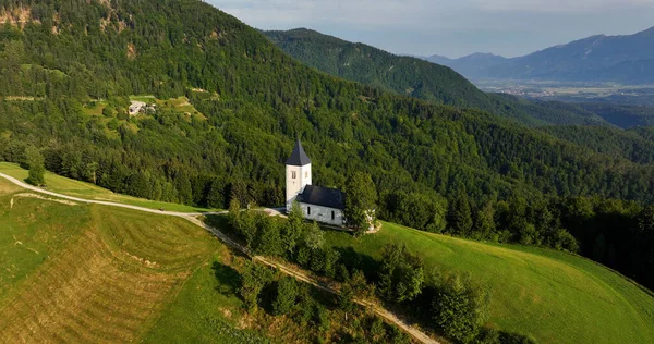 Slovenya, St. Primoz Kilisesi, Jamnik, yukarıdan muhteşem gündoğumu manzarası, Kranj, Gorenjska 'daki yeşil tepedeki ikonik kilise