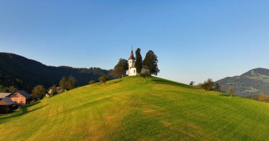 Slovenya, St. Thomas kilisesinin tepedeki havadan görünüşü, sabahın erken saatlerinde Skofja Loka yakınlarında.
