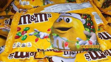 New York, ABD - Aralık 2021: M and M 's, süpermarkette sarı festival paketi içinde çok renkli çikolatalı abur cubur markası. Noel ve yeni yıl süslemeleri m & m 'nin çelenkli paketinde