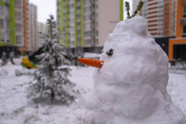 Havuç burunlu beyaz kardan adam, kardan yapılmış, kışın apartman dairesinin arka bahçesinde kardan adam. Noel hazırlığı 